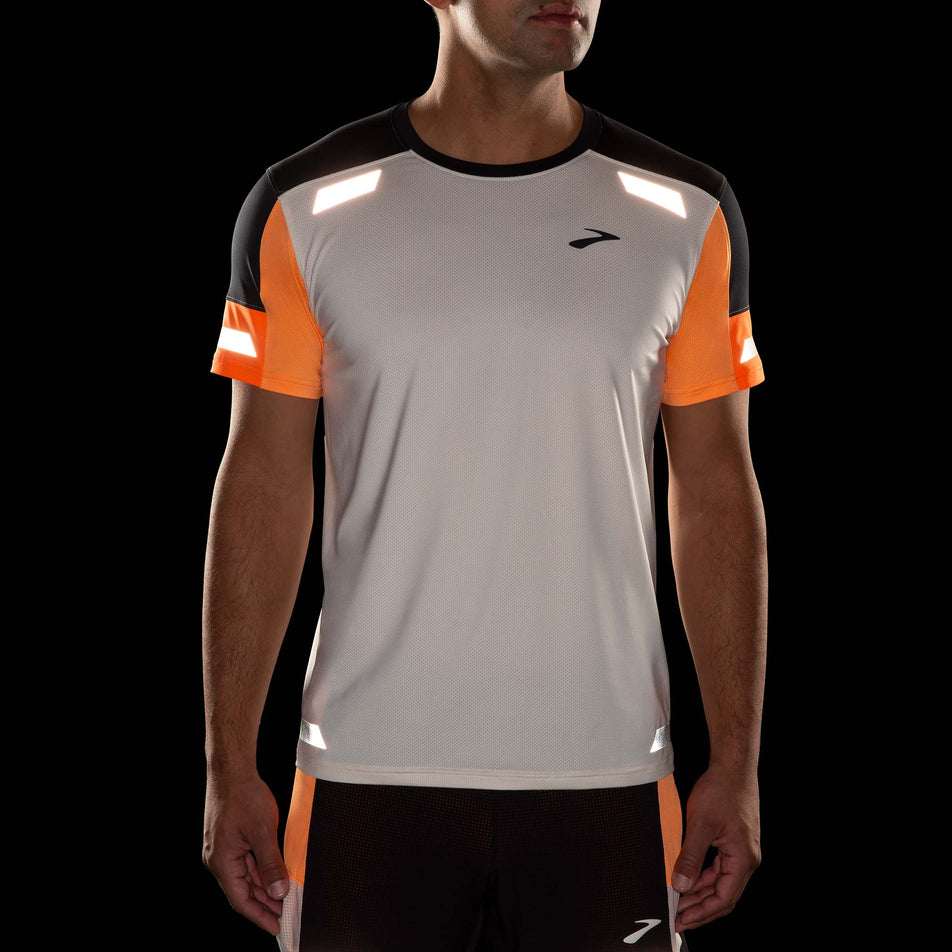 Front view of a model wearing the Brooks Men's Run Visible Short Sleeve 2.0 in the Ecru/Fluoro Flash/Black colourway. Model is also wearing Brooks shorts. Reflective strips are reflecting artificial light. (8499431800994)