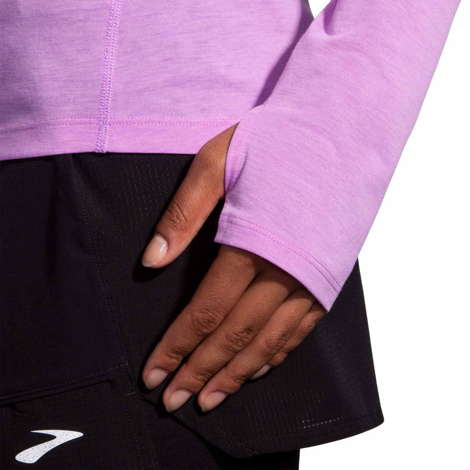 Close-up view of the thumb loop detail at the end of the left sleeve on a Brooks Women's High Point Long Sleeve Top in the Bright Purple colourway. Top is being worn by a model. (8037740609698)