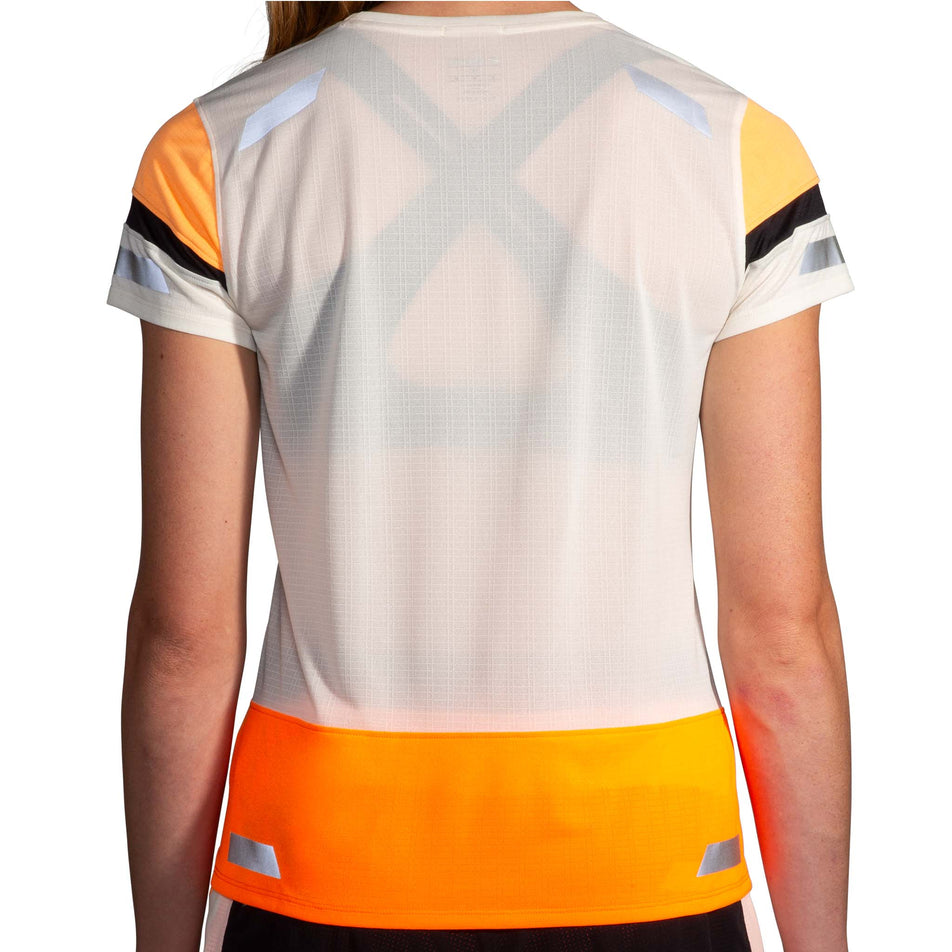 Back view of a model wearing the Brooks Women's Run Visible Short Sleeve 2.0 in the Ecru/Fluoro Flash/Black colourway. Model is also wearing Brooks shorts. (8499450806434)