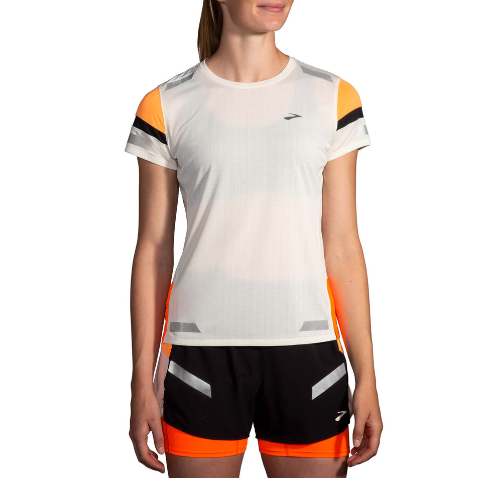 Front view of a model wearing the Brooks Women's Run Visible Short Sleeve 2.0 in the Ecru/Fluoro Flash/Black colourway. Model is also wearing Brooks shorts. (8499450806434)