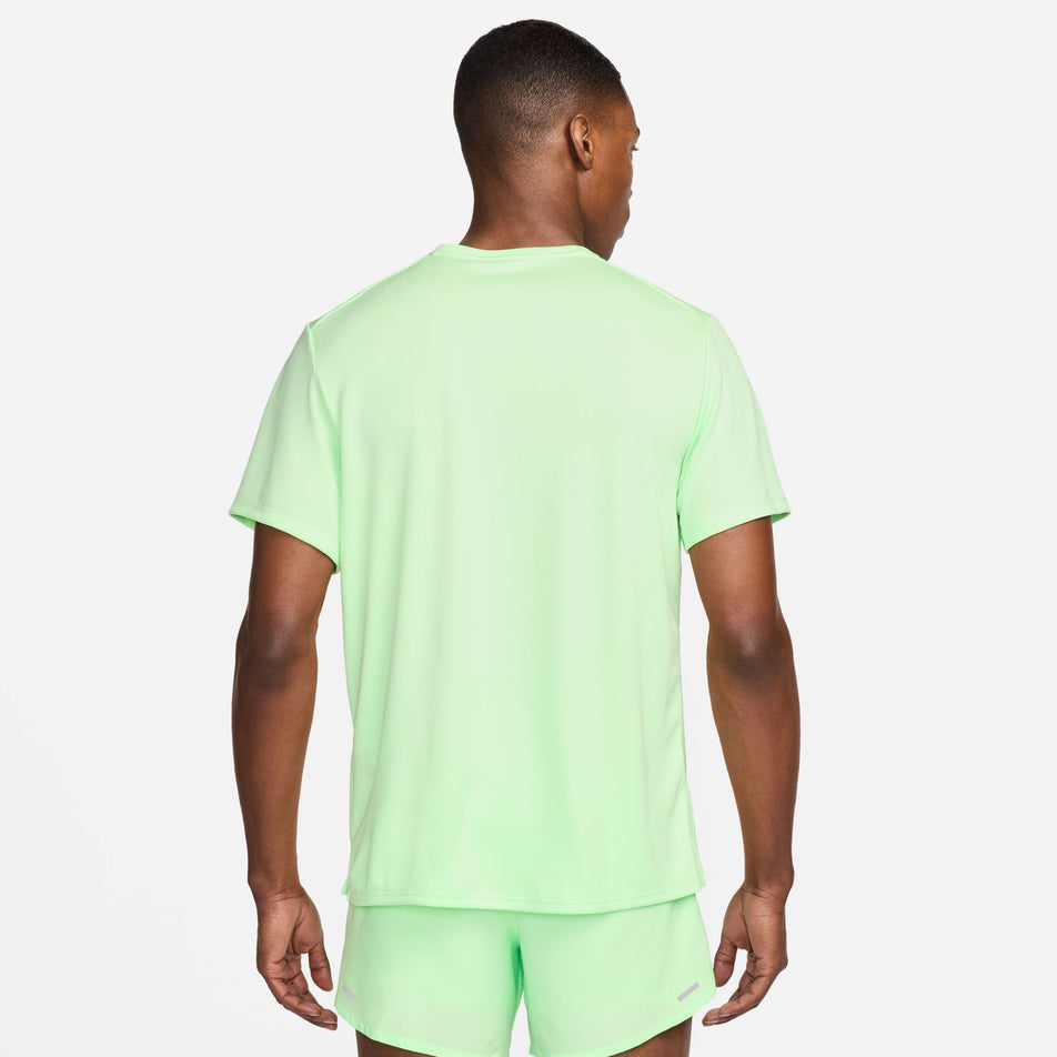 Back view of a model wearing a Nike Men's Miler Dri-FIT UV Short-Sleeve Running Top in the Vapor Green/Reflective Silv colourway. Model is also wearing Nike running shorts. (8399203467426)