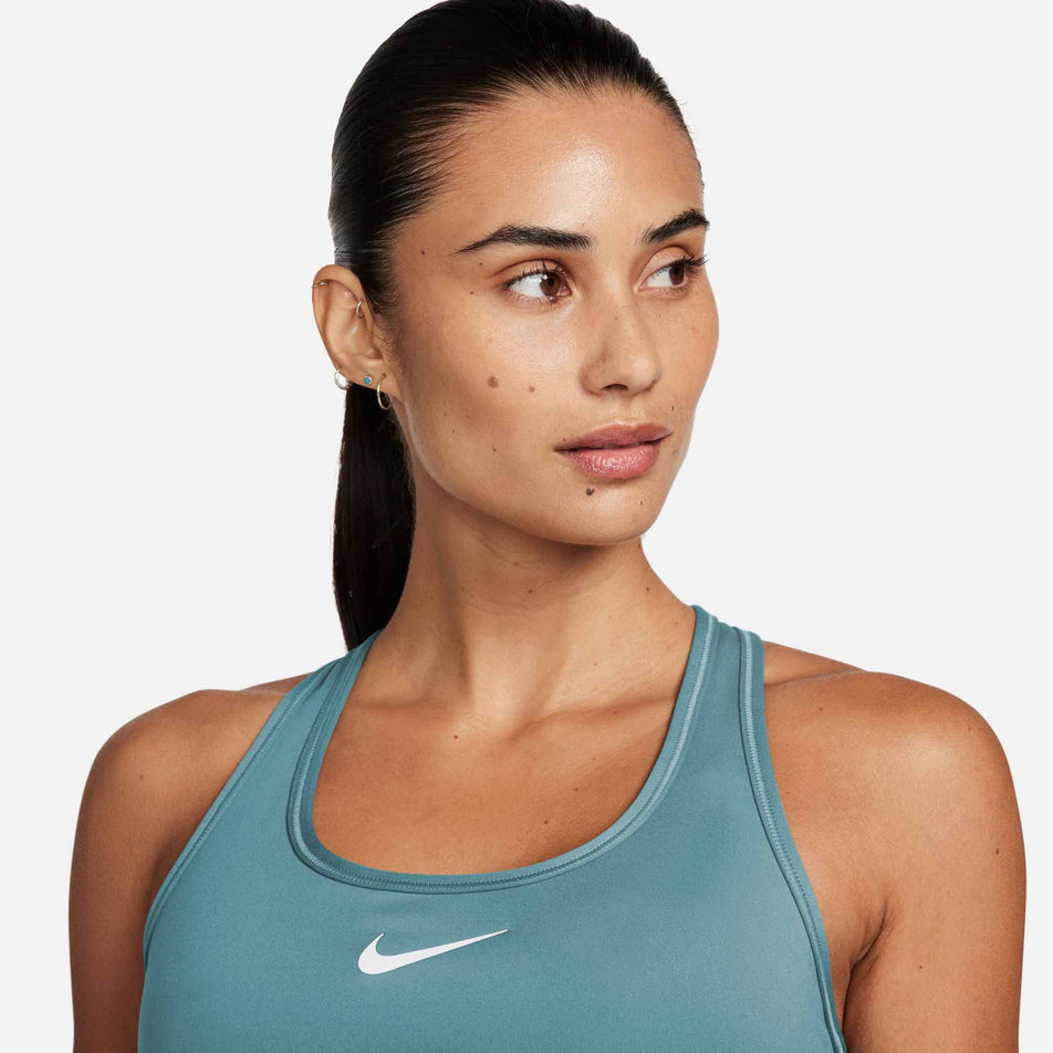 Close-up front view of a model wearing a Nike Women's Swoosh Medium Support Padded Sports Bra in the Denim Turq/White colourway (8399176007842)