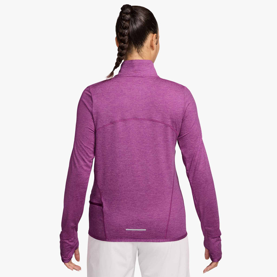 Back view of a model wearing Nike Women's Swift Element UV Protection 1/4-Zip Running Top in the Hot Fuchsia/Plum Dust/Reflective Silv colourway. Model is also wearing White Nike trousers. (8497624383650)