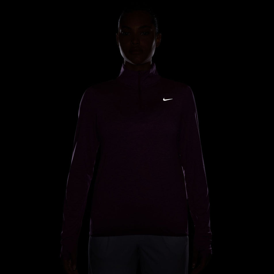 The reflective Swoosh on the Nike Women's Swift Element UV Protection 1/4-Zip Running Top in the Hot Fuchsia/Plum Dust/Reflective Silv colourway.  (8497624383650)