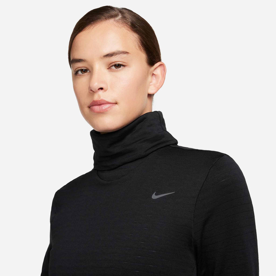 The front of the upper body of a model wearing a Nike Women's Swift Element Therma-FIT Turtleneck Running Top in the Black/Reflective Silver colourway.  (8497637752994)