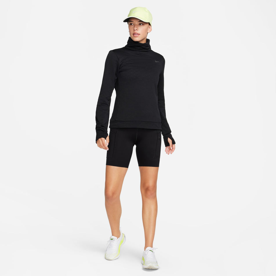 Front view of a model wearing a Nike Women's Swift Element Therma-FIT Turtleneck Running Top in the Black/Reflective Silver colourway. Model is also wearing black Nike shorts and Nike shoes.(8497637752994)