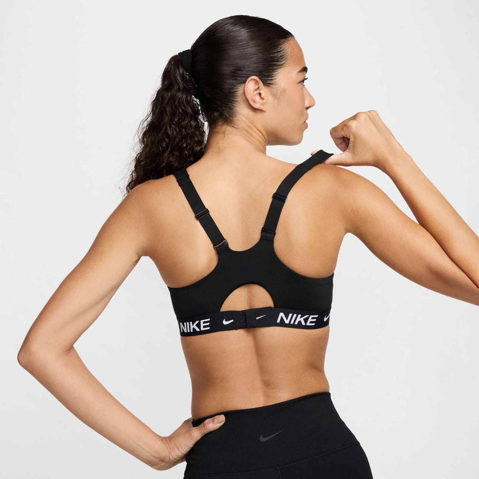 Back view of a model wearing a Nike  Women's Indy High Support Padded Adjustable Sports Bra in the Black/Black/White colourway. (8495571435682)