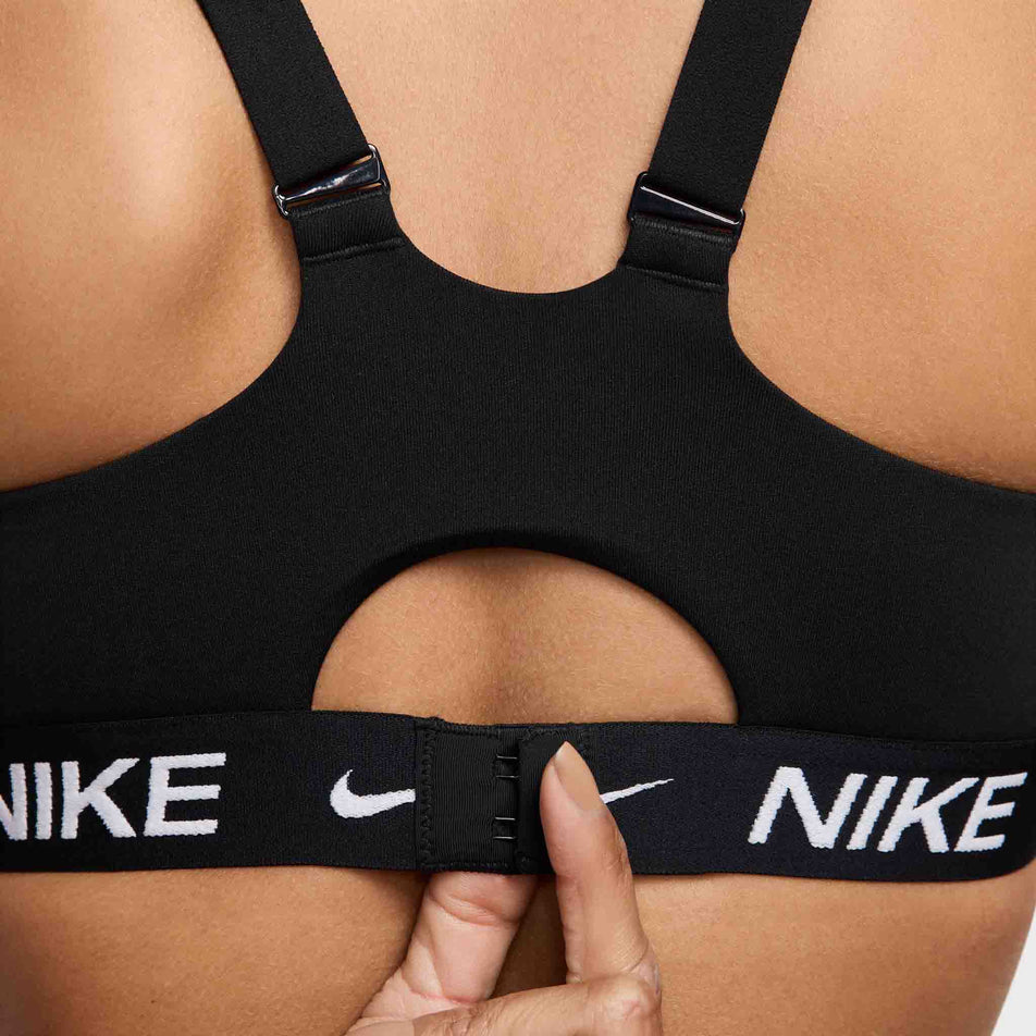 Close-up view of the back of a model wearing a Nike  Women's Indy High Support Padded Adjustable Sports Bra in the Black/Black/White colourway. (8495571435682)