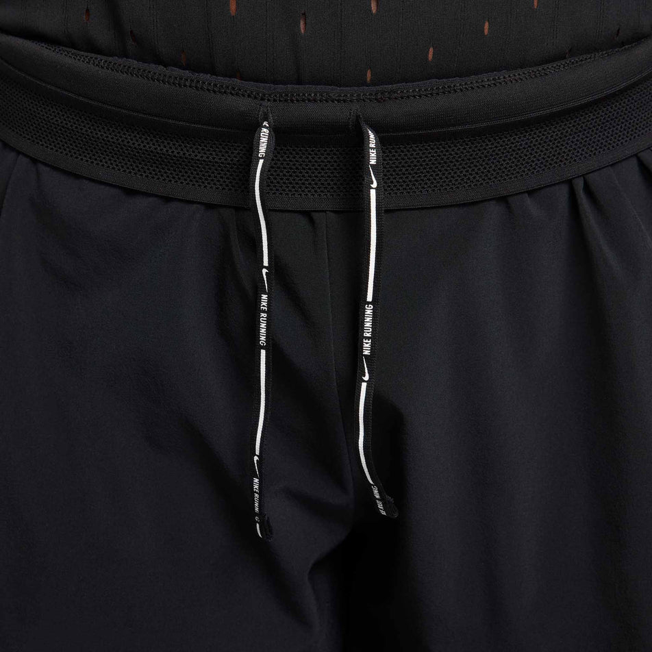 A model highlighting the drawcord on the inside of the waistband of a pair of Nike Women's AeroSwift Dri-FIT ADV Mid-Rise Brief-Lined 3