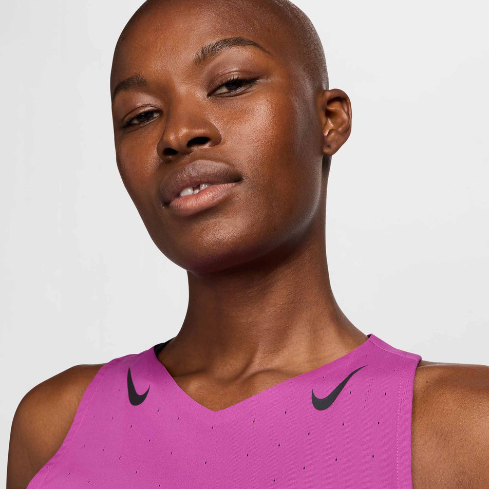 Close-up of the upper-front part of a Nike Women's AeroSwift Dri-FIT ADV Running Singlet in the Hot Fuchsia/Black colourway. The top is being worn by a model. (8492375015586)