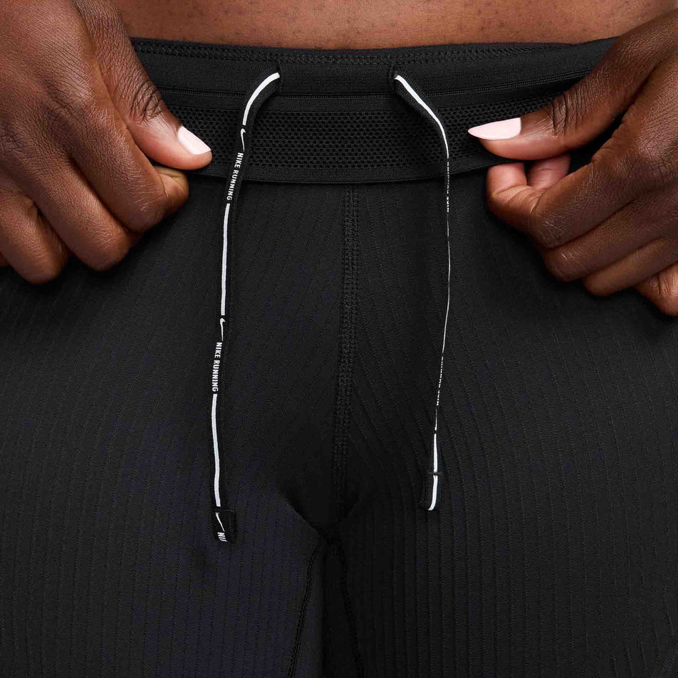 A model highlighting the drawcord on the waistband of a pair of Nike Women's AeroSwift Dri-FIT ADV Mid-Rise 5