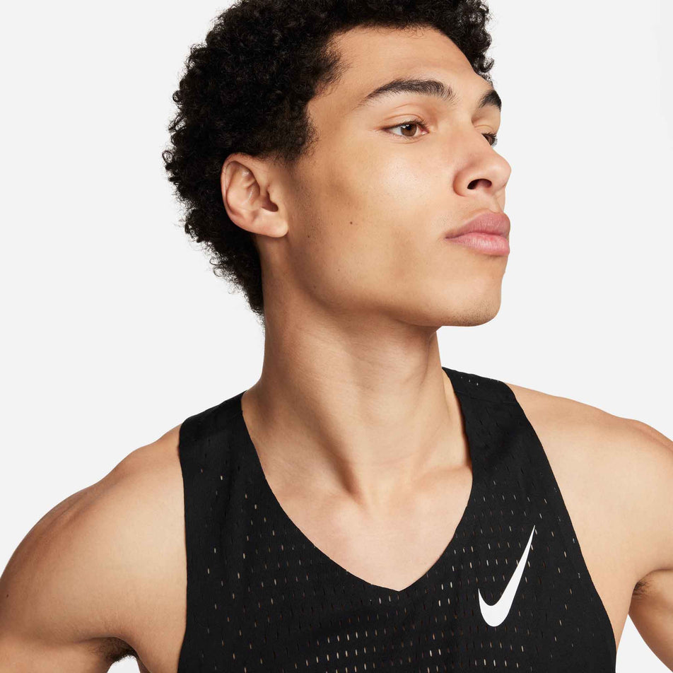 Close-up front view of a model wearing a Nike Men's AeroSwift Dri-FIT ADV Running Singlet in the Black/Summit White colourway. Only the upper part of the singlet can be seen in the image. (8393096462498)