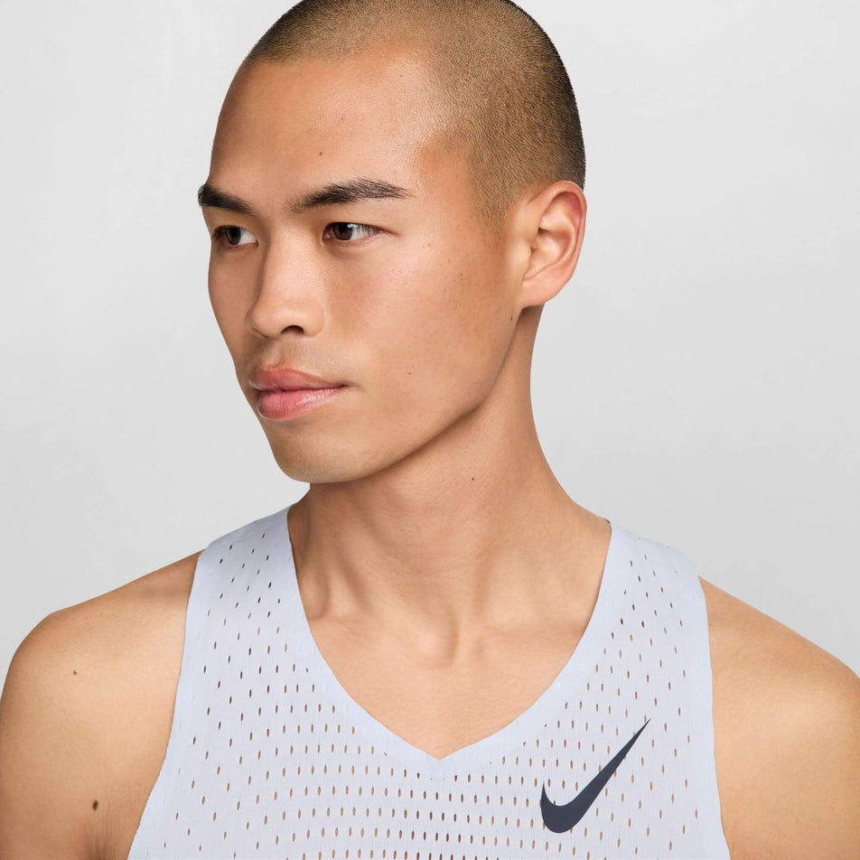 Front view of a model wearing a Nike Men's AeroSwift Dri-FIT ADV Running Singlet in the Football Grey/Dark Obsidian colourway. Only the upper part of the singlet can be seen in the image. (8399202058402)