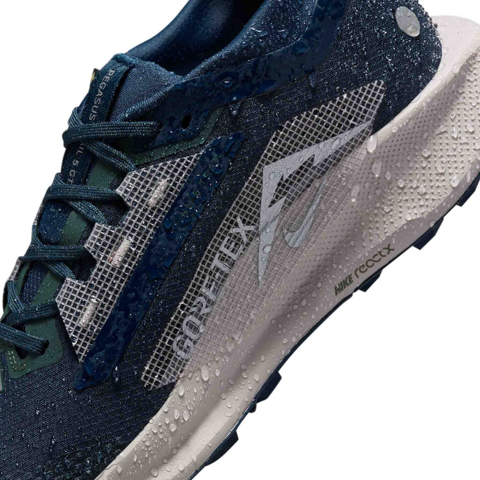 Water droplets on the outside of the right shoe from a pair of Nike Women's Pegasus Trail 5 GORE-TEX Waterproof Trail Running Shoes in the Armory Navy/Armory Navy-Vintage Green colourway. (8503772643490)