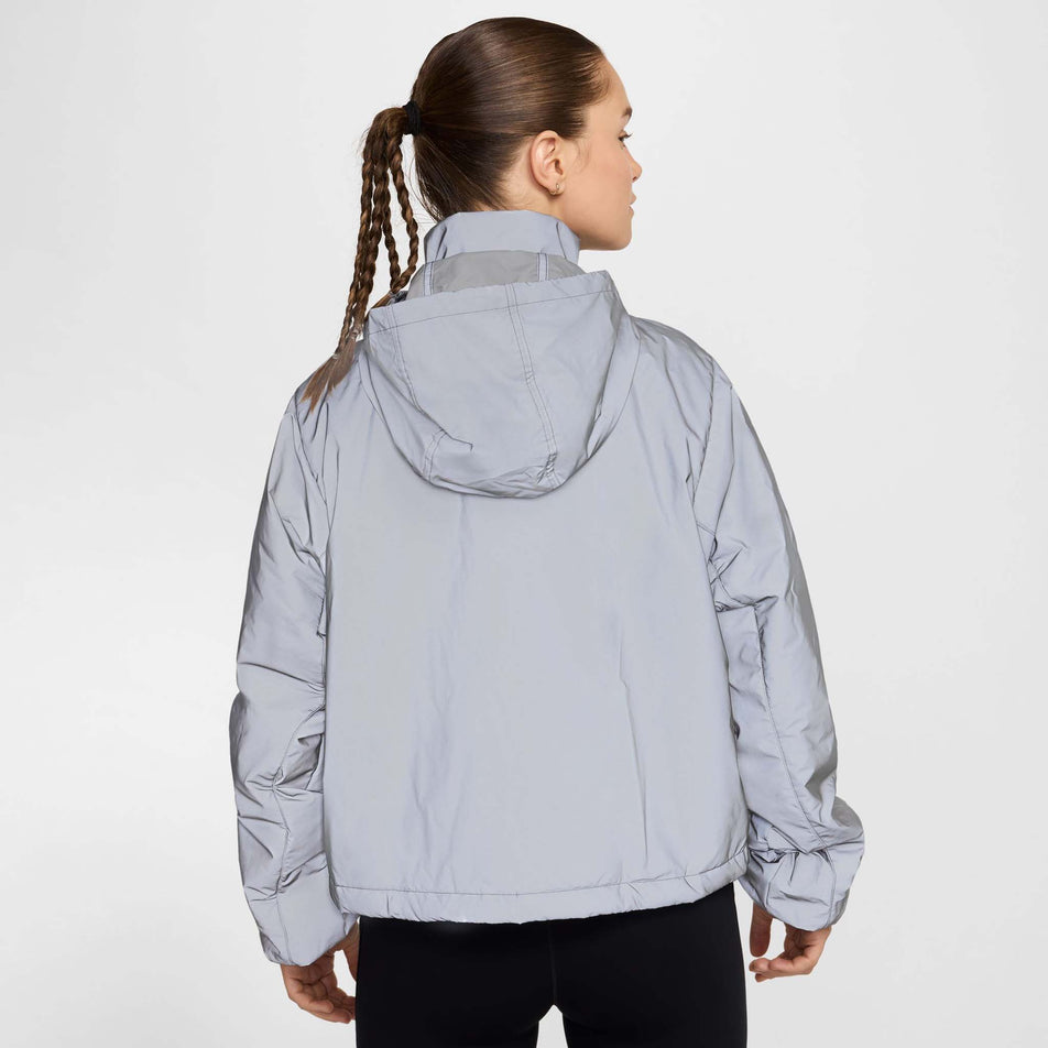 Back view of a model wearing Nike Women's Running Division Therma-FIT Reflective Running Jacket in the Black/Reflective Silv/Refblk colourway. Model is also wearing black Nike tights.  (8497648730274)