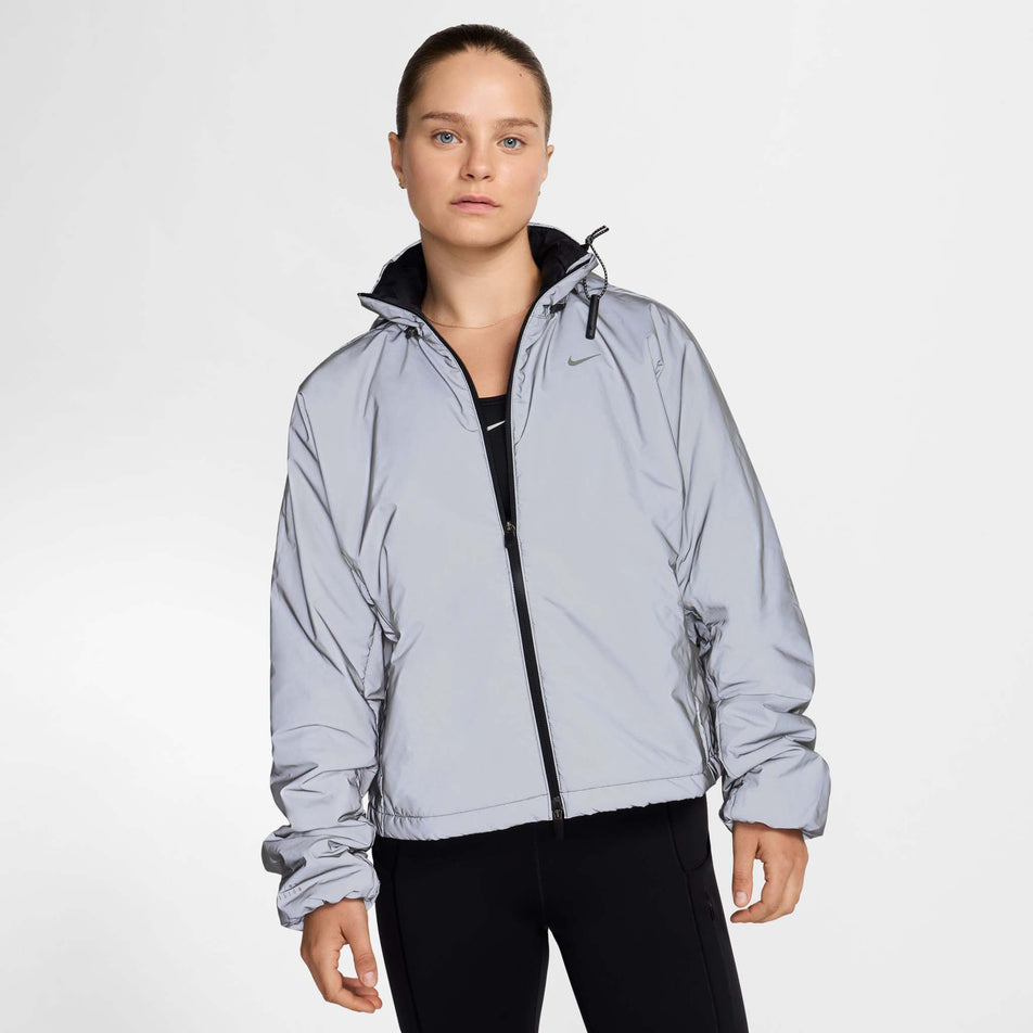 Front view of a model wearing Nike Women's Running Division Therma-FIT Reflective Running Jacket in the Black/Reflective Silv/Refblk colourway. Model is also wearing black Nike tights. (8497648730274)