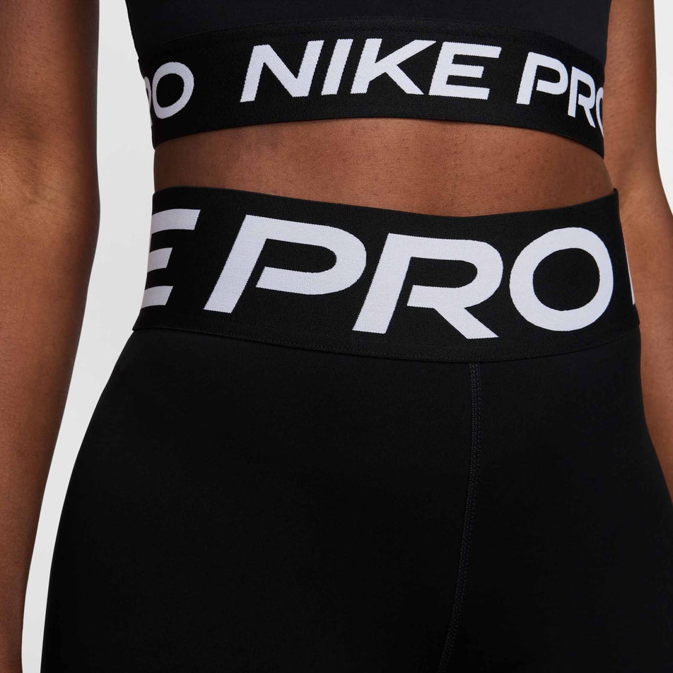 Close-up front view of the waistband on a pair of Nike Women's Pro Sculpt High-Waisted Full-Length Leggings in the Black/White colourway. Leggings are being worn by a model who is also wearing a top. (8399168143522)