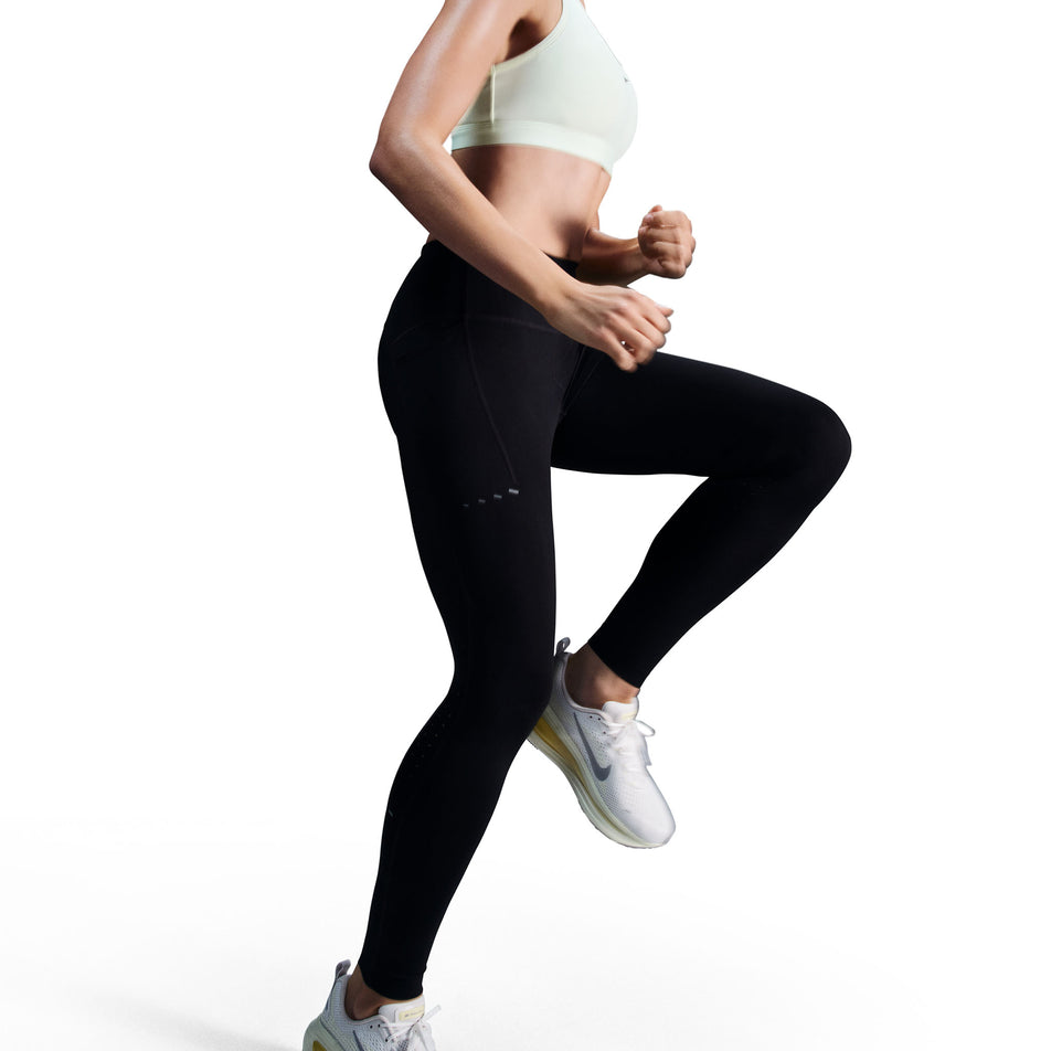 Angled view of a model wearing a pair of Nike Women's Swift Dri-FIT High Rise 7/8 Running Tights in the Black/Reflective Silver colourway.(8560773759138)