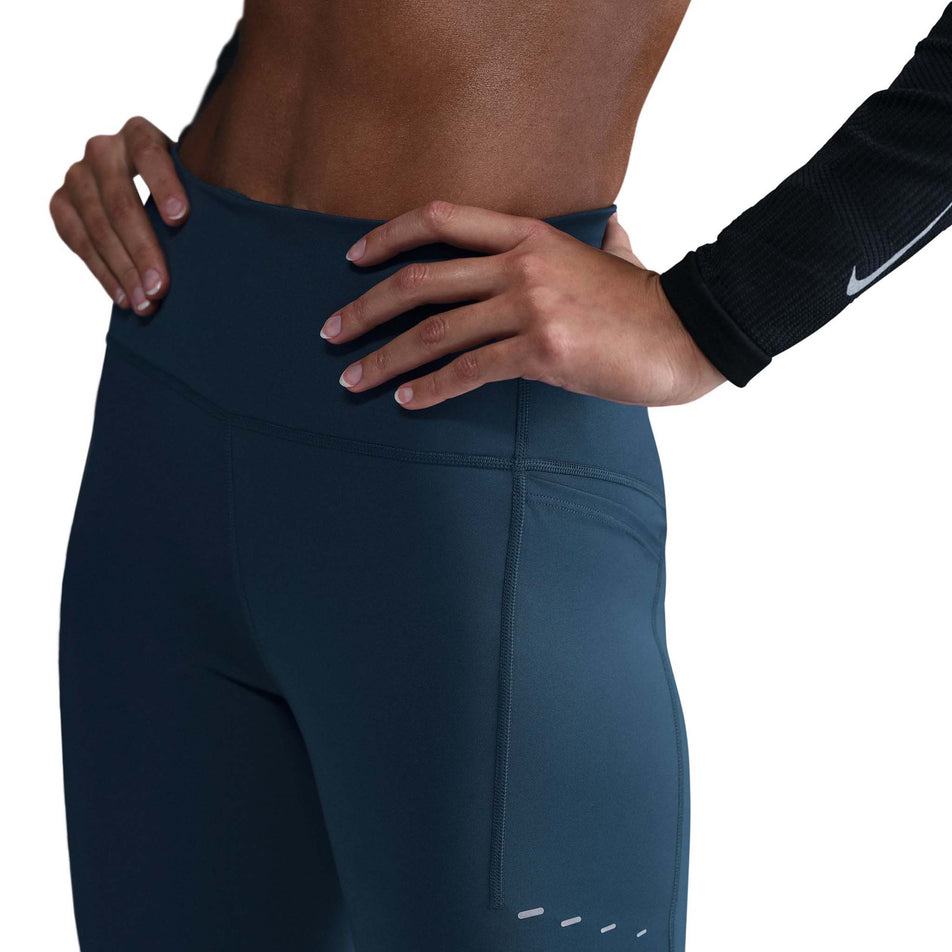 Angled view of the top half of the Nike Women's Swift Dri-FIT High Rise 7/8 Running Tights in the Armory Navy/Reflective Silver colourway. (8560458563746)