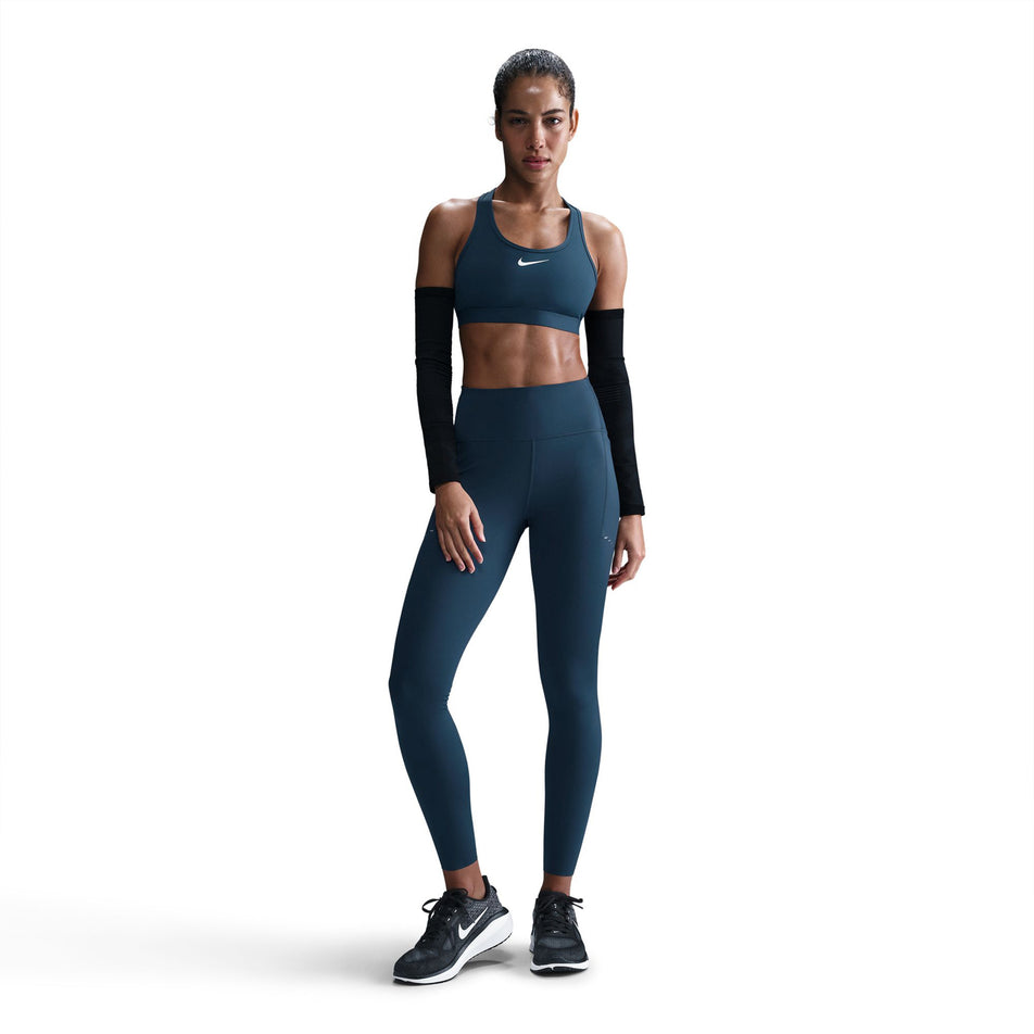 Front view of a model wearing a pair of Nike Women's Swift Dri-FIT High Rise 7/8 Running Tights in the Armory Navy/Reflective Silver colourway. (8560458563746)