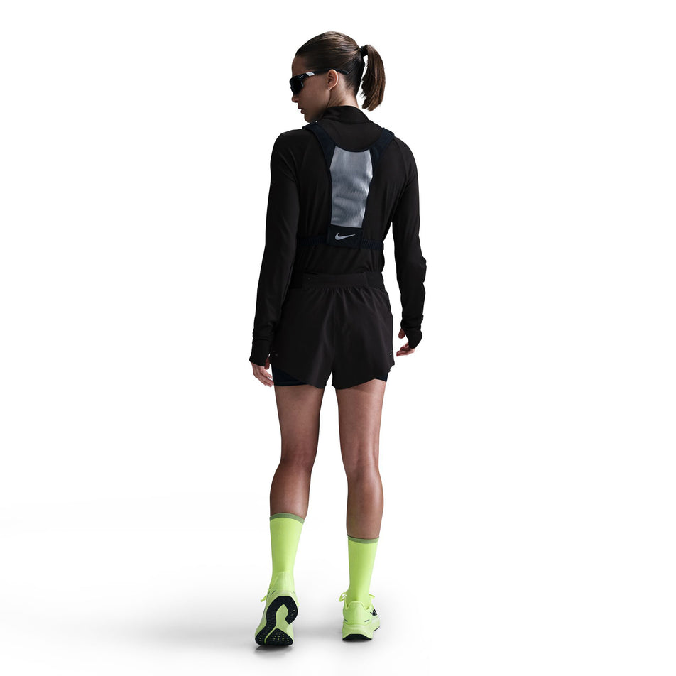 Back view of a model wearing a pair of Nike Women's Swift Dri-FIT Mid-Rise 2-in-1 Running Shorts in the Black/Reflective Silver colourway. (8560446046370)