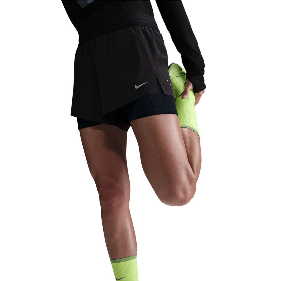 Front view of a model wearing a pair of Nike Women's Swift Dri-FIT Mid-Rise 2-in-1 Running Shorts in the Black/Reflective Silver colourway. (8560446046370)