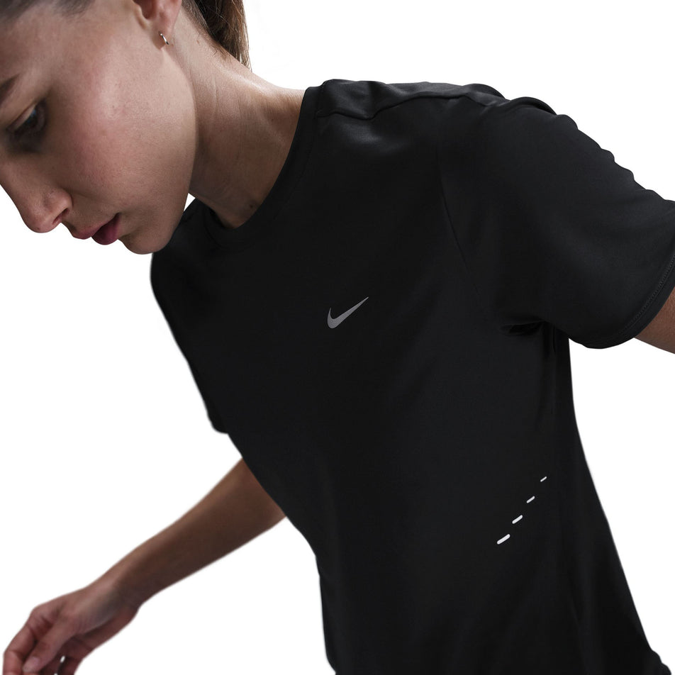 Angled front view of a model wearing a Nike Women's Swift Dri-FIT Short-Sleeve Running Top in the Black/Reflective Silver colourway.  (8560479404194)