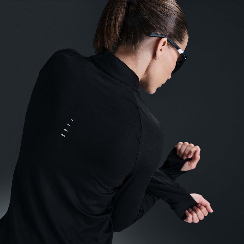 Back view of a model wearing a Nike Women's Swift Fri-FIT UV Half-Zip Long Sleeve Running Top in the Black/Reflective Silver colourway. (8560809312418)