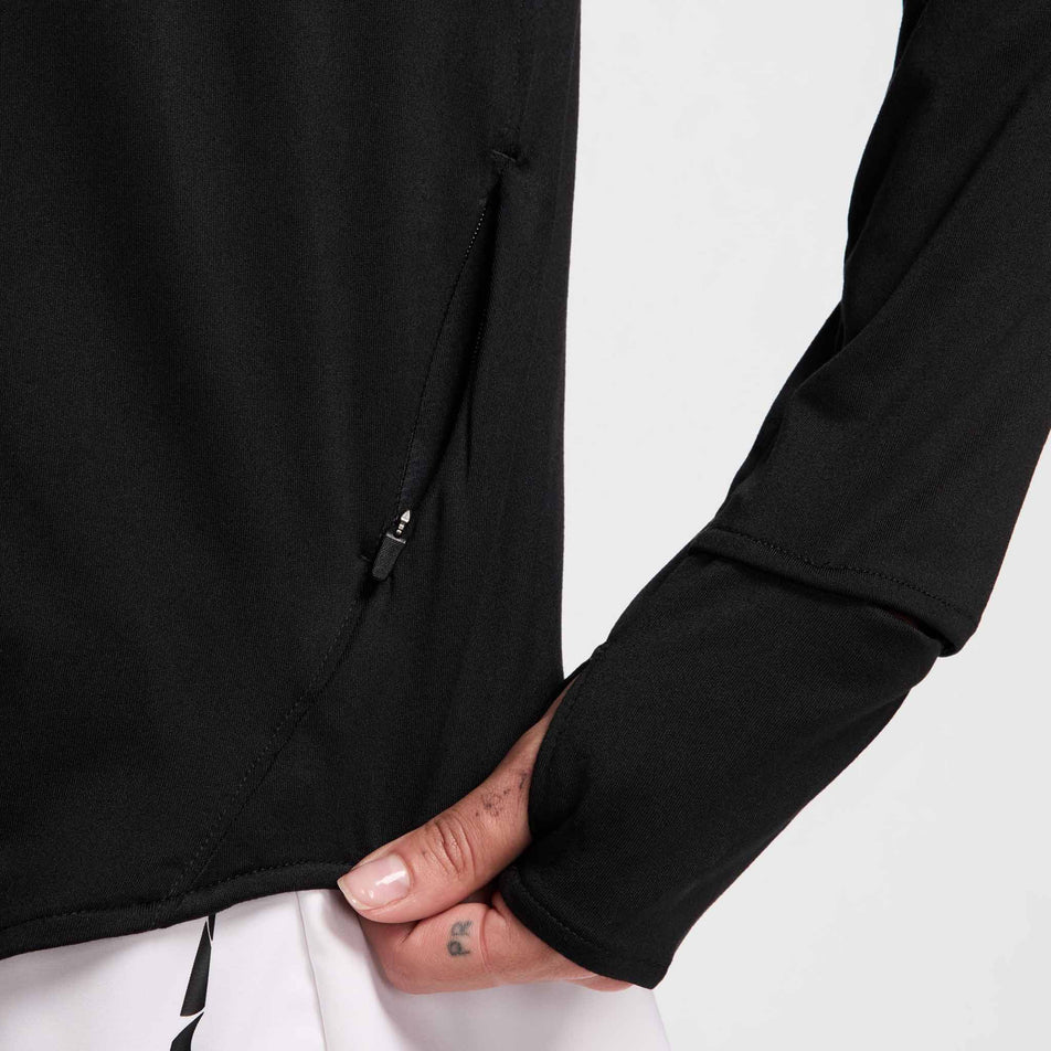 Close up view of the zippered pocket on the left side of the Nike Women's Swift Fri-FIT UV Half-Zip Long Sleeve Running Top in the Black/Reflective Silver colourway. (8560809312418)