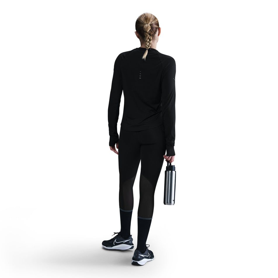 Back view of a model wearing a Nike Women's Swift Dri-FIT UV Long-Sleeve Crew Running Top in the Black/Reflective Silver colourway. (8560750264482)