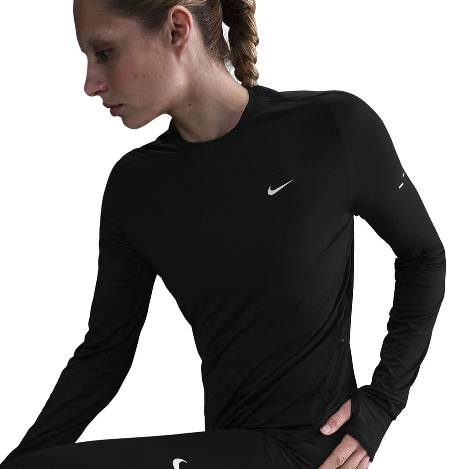 Angled view of a model wearing a Nike Women's Swift Dri-FIT UV Long-Sleeve Crew Running Top in the Black/Reflective Silver colourway. (8560750264482)