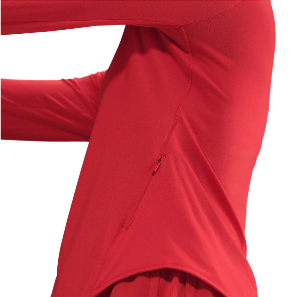 Close up view of the zip pocket on the left side of the Nike Women's Swift Dri-FIT UV Long-Sleeve Crew Running Top in the Light Crimson/Reflective Silver colourway. (8560789553314)