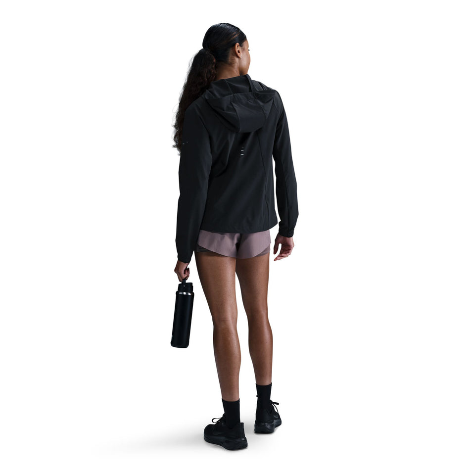 Back view of a model wearing a Nike Women's Swift Repel Packable Running Jacket in the Black/Reflective Silver colourway.(8560817635490)