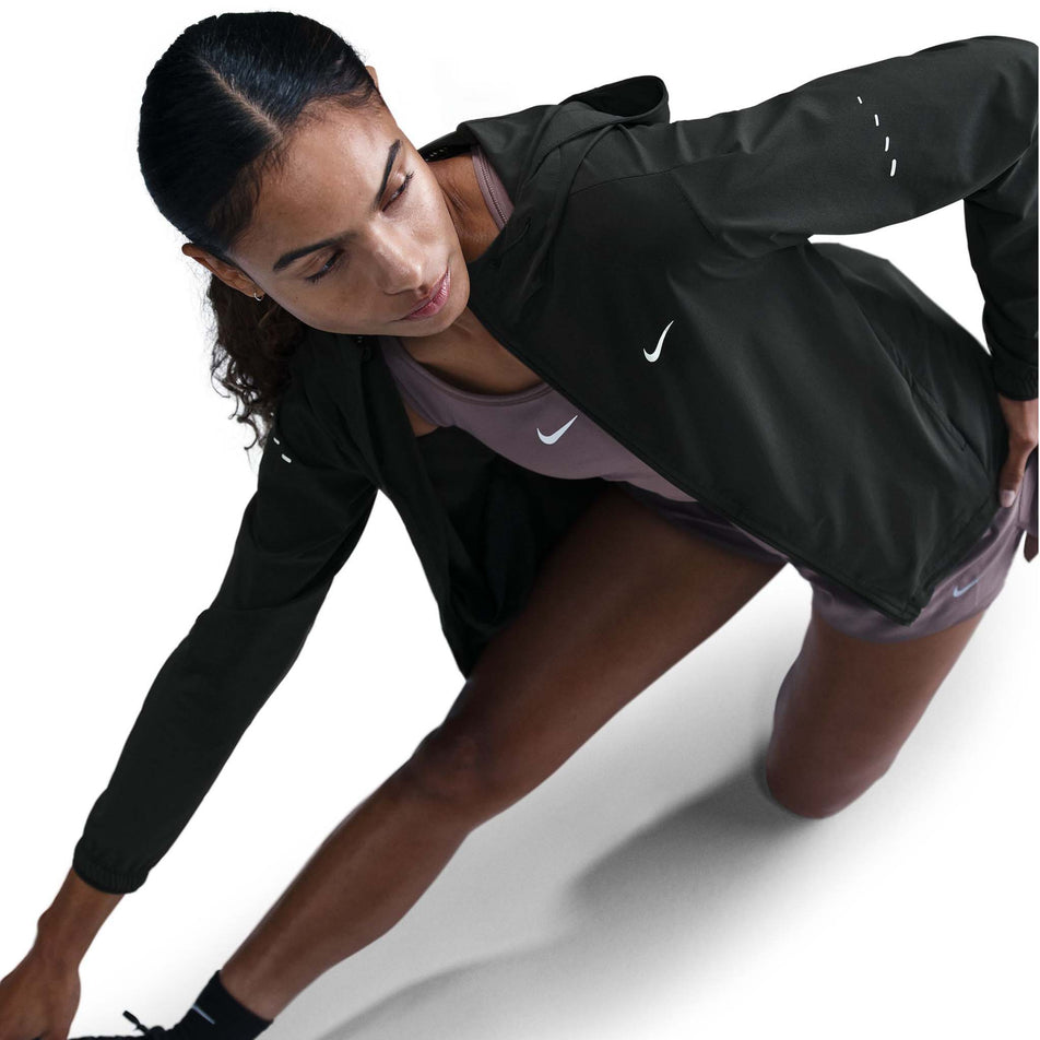 Angled view of a model wearing a Nike Women's Swift Repel Packable Running Jacket in the Black/Reflective Silver colourway.  (8560817635490)