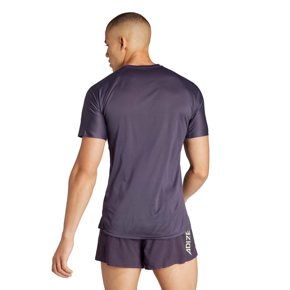 Back view of a model wearing an adidas Men's Adizero Running T-Shirt in the Aurora Black/Green Spark colourway. Model is also wearing adidas running shorts. (8312050548898)