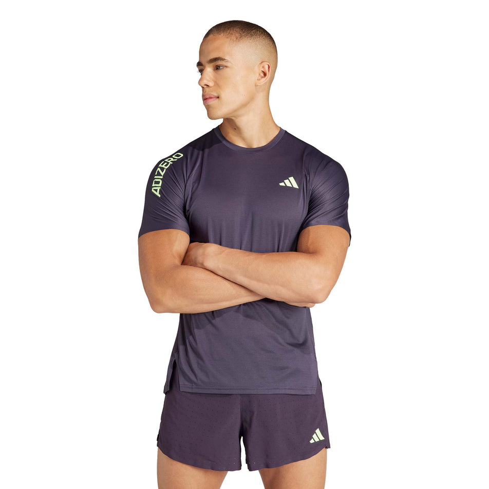 Front view of a model wearing an adidas Men's Adizero Running T-Shirt in the Aurora Black/Green Spark colourway. Model is also wearing adidas running shorts. (8312050548898)