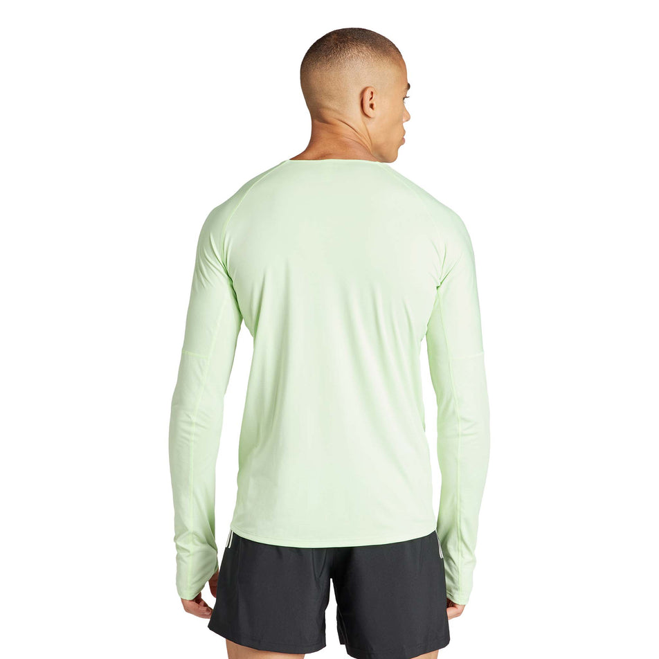 Back view of a model wearing an adidas Men's Adizero Running Long Sleeve Top in the Semi Green Spark/Aurora Black colourway. Model is also wearing adidas running shorts. (8312060969122)