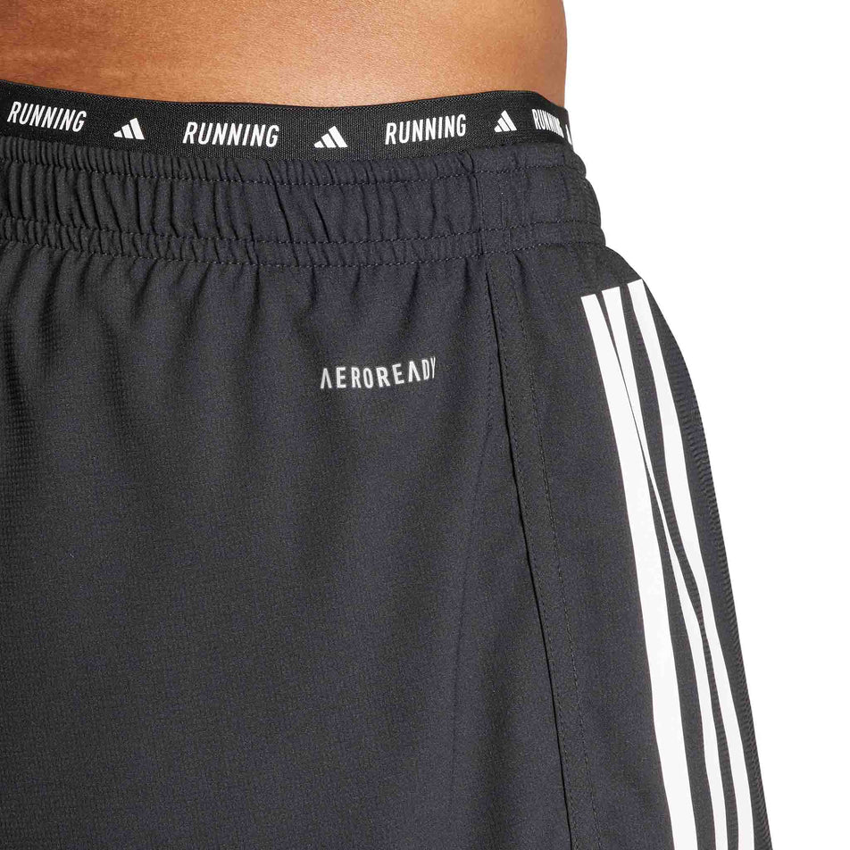 Close-up of the waistband detail on a pair of adidas Men's Own The Run 3-Stripes 2-In-1 Shorts in the black colourway. Shorts are being worn by a model. (8449469448354)