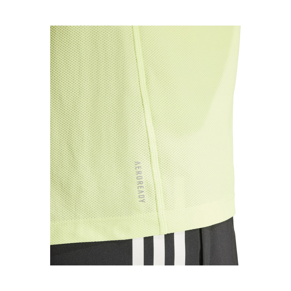 The AEROREADY logo, sitting just above the lower-left hem of an adidas Men's Own The Run T-Shirt in the Pulse Lime colourway. Top is being worn by a model. (8457446949026)