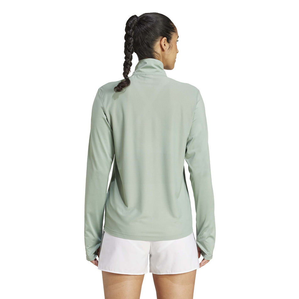 Back view of a model wearing the adidas Women's Own The Run Base Half Zip in the Silver Green colourway. (8567465181346)