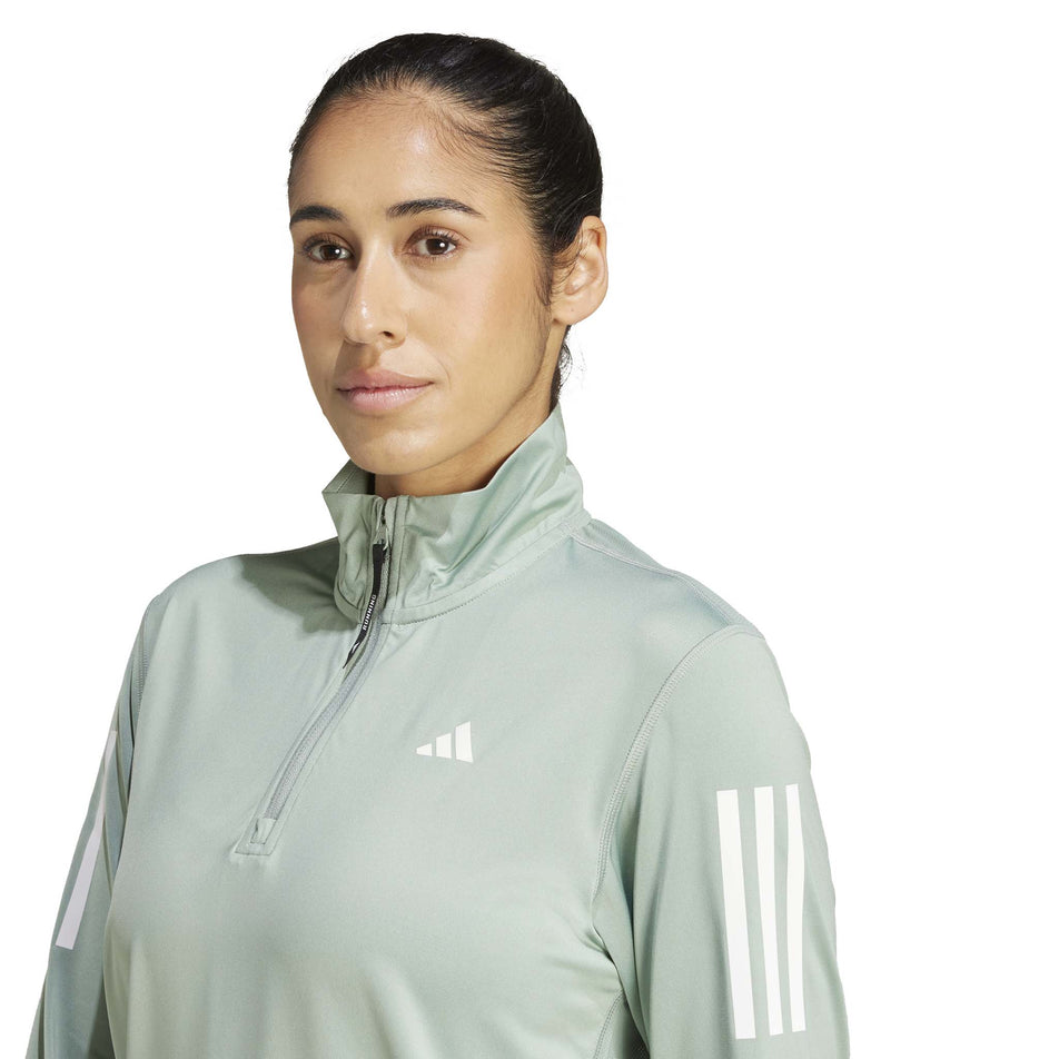 Front view of a model wearing the adidas Women's Own The Run Base Half Zip in the Silver Green colourway. (8567465181346)