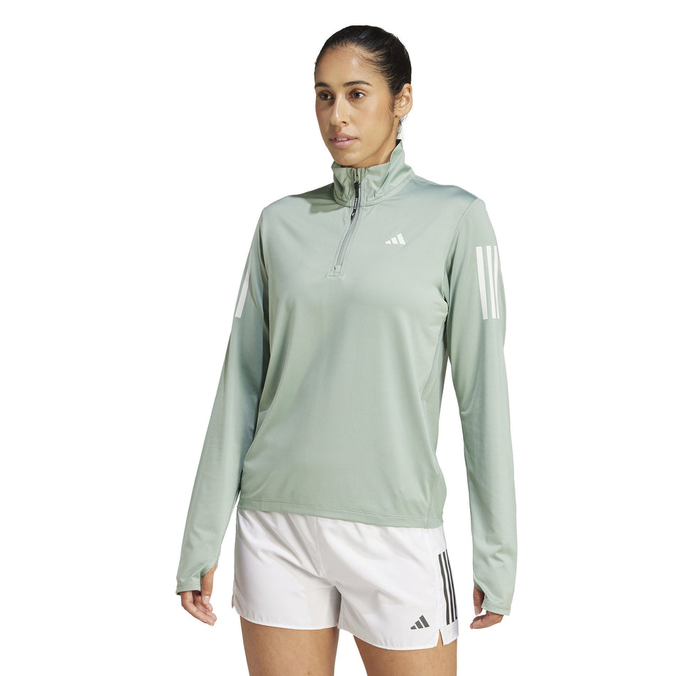 Front view of a model wearing the adidas Women's Own The Run Base Half Zip in the Silver Green colourway. (8567465181346) 