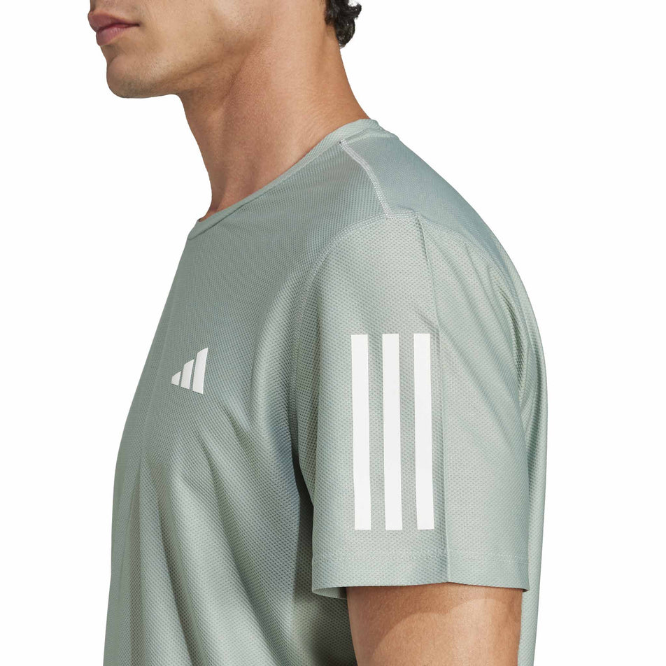 Side view of a model wearing the adidas Men's Own The Run Base Tee in the Silver Green colourway.  (8566974873762)