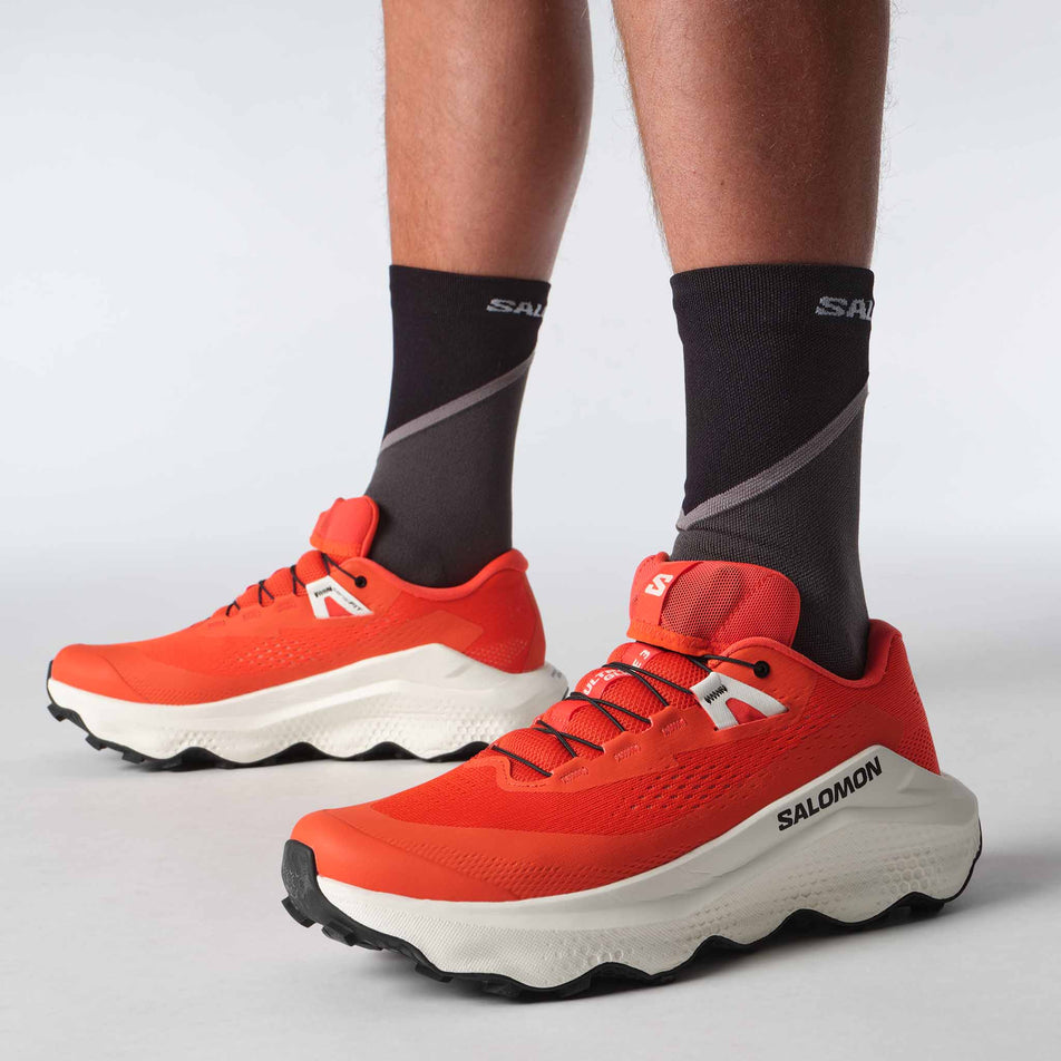 A model wearing a pair of Salomon Men's Ultra Glide 3 Running Shoes in the Cherry Tomato colourway. (8576003637410)