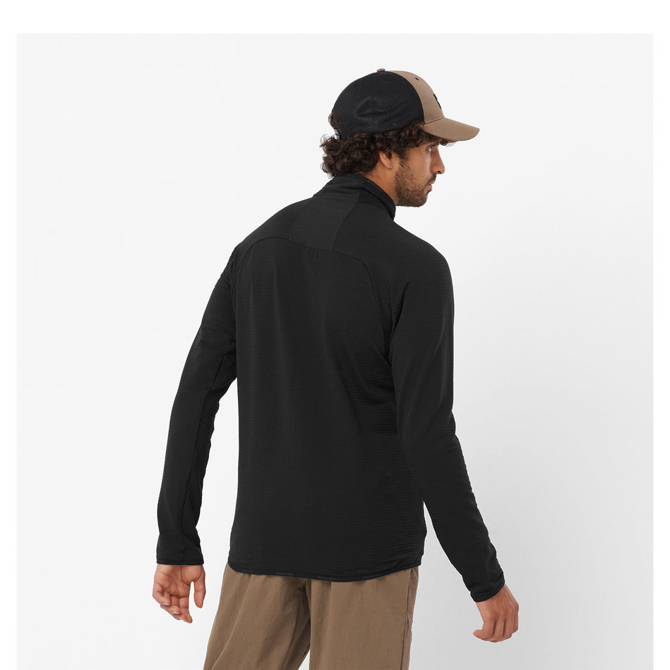 Back view of a model wearing a Salomon Men's Essential Lightwarm Full Zip Midlayer Jacket in the Deep Black colourway. Model is also wearing legwear and a cap. (8464264200354)