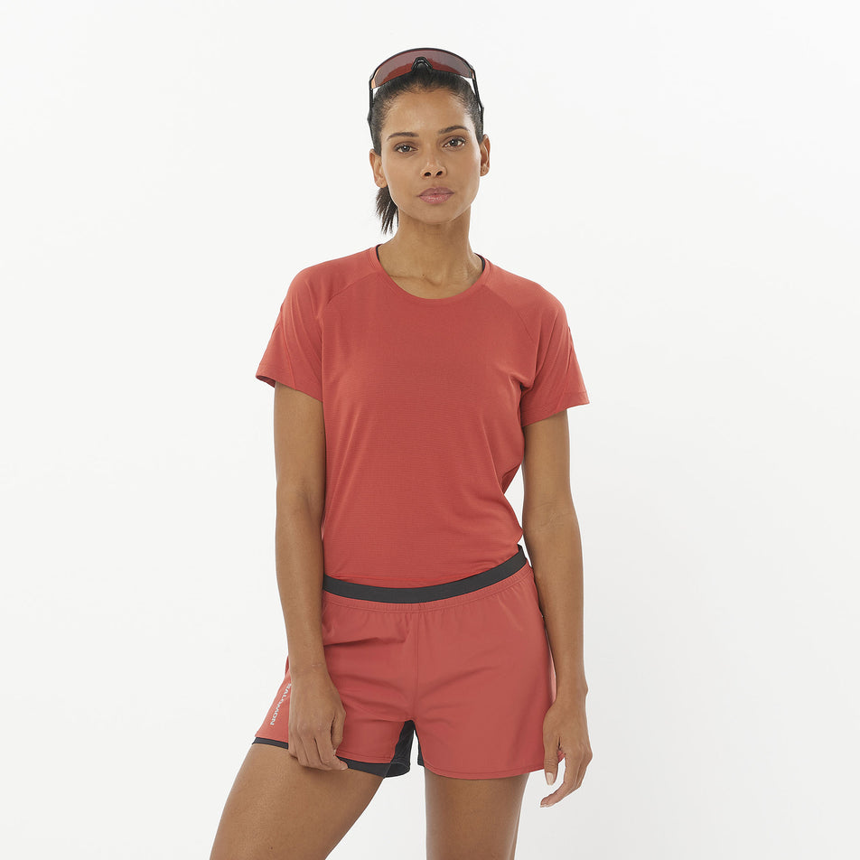 Front view of a model wearing the Salomon Women's Cross Run Short Sleeve T-Shirt in the Tandoori Spice colourway. Model is also wearing shorts and sunglasses. (8509491183778)