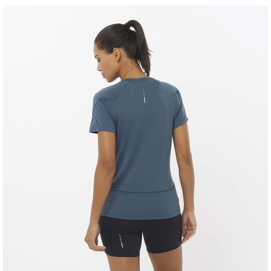 Back view of a model wearing a Salomon Women's Cross Run Short Sleeve T-Shirt in the Midnight Navy colourway. Model is also wearing Salomon shorts. (8464204693666)