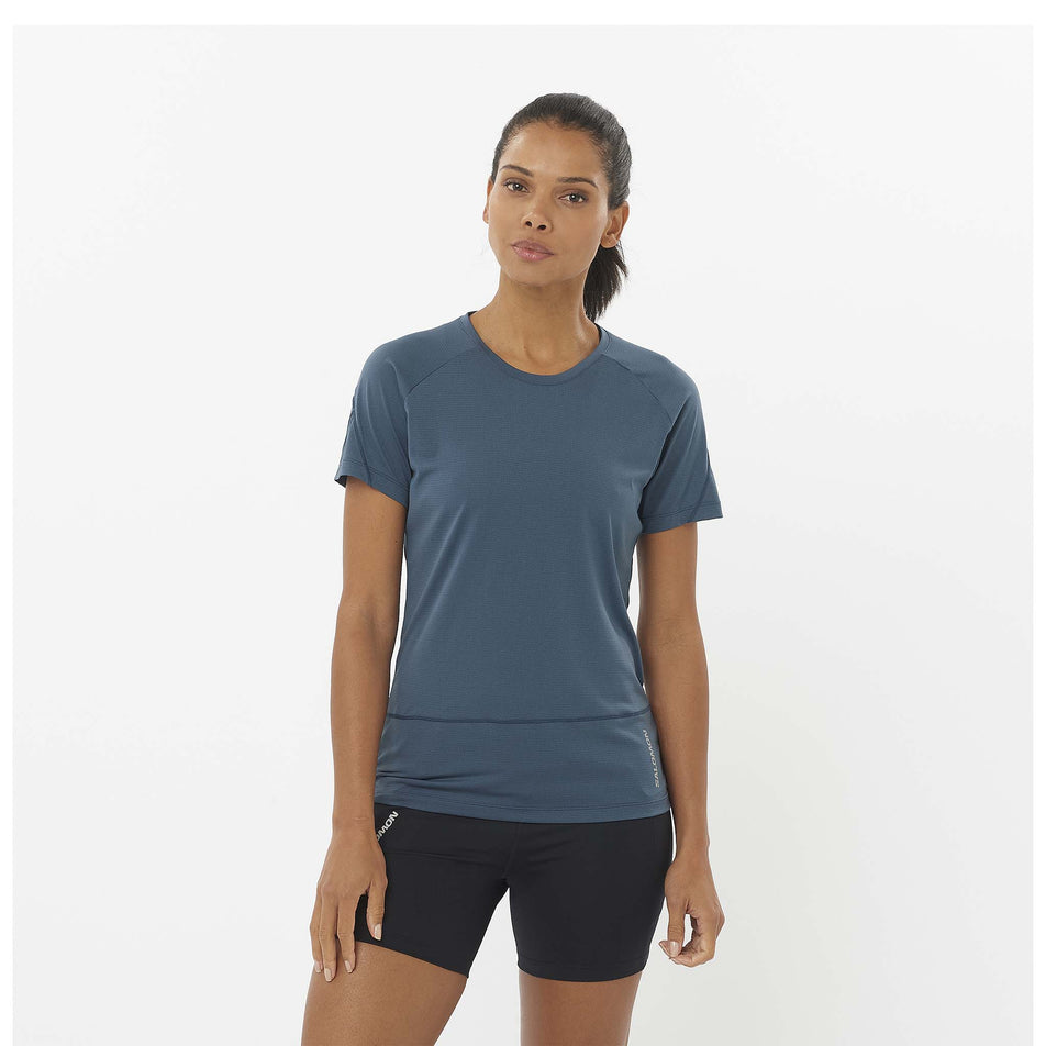 Front view of a model wearing a Salomon Women's Cross Run Short Sleeve T-Shirt in the Midnight Navy colourway. Model is also wearing Salomon shorts. (8464204693666)