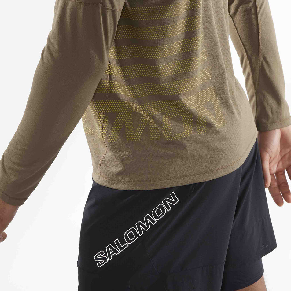 Close-up view of the lower left back of the Salomon Men's Sense Aero Graphic Long-Sleeve T-Shirt in the Shitake/Sulphur Spring colourway. Model is also wearing shorts. (8509586014370)