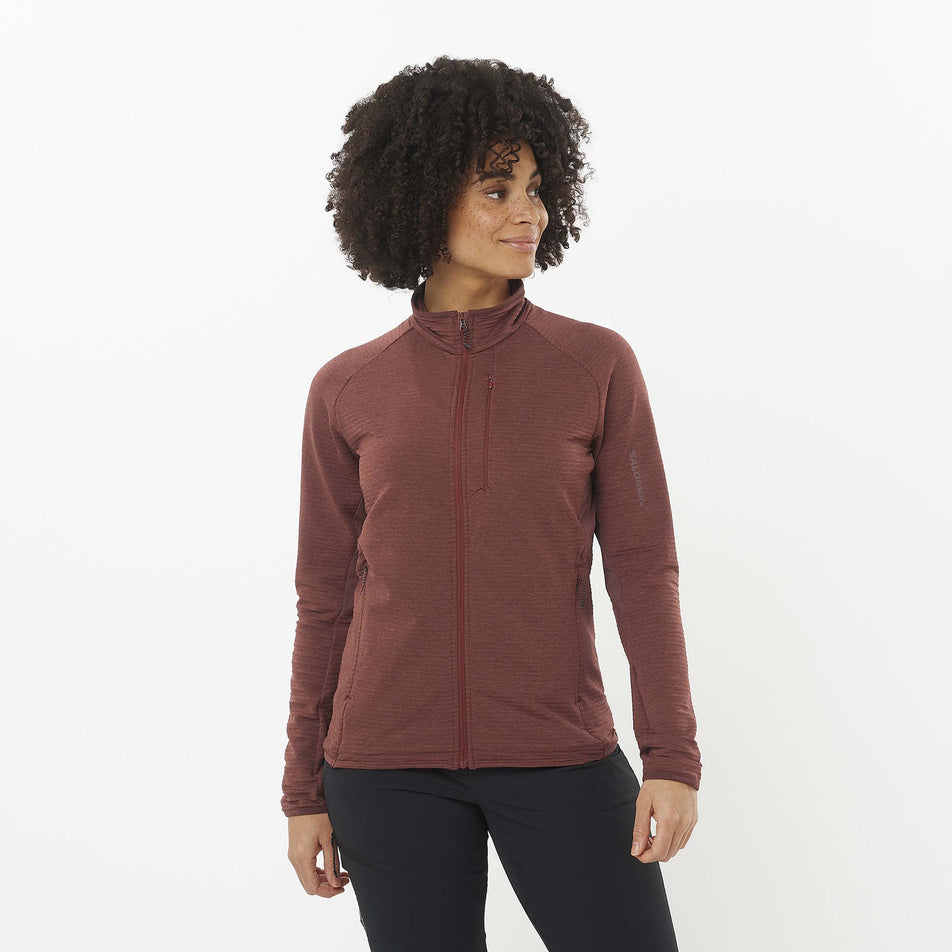 Front view of a model wearing the Salomon Women's Essential Lightwarm Full Zip Midlayer Jacket in the Rum Raisin colourway. Model is also wearing leggings. (8509475389602)